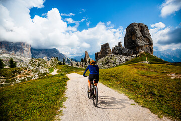 Woman ride electric mountain bikes in the Dolomites in Italy. Mountain biking adventure on beautiful mountain trails. - 589891190