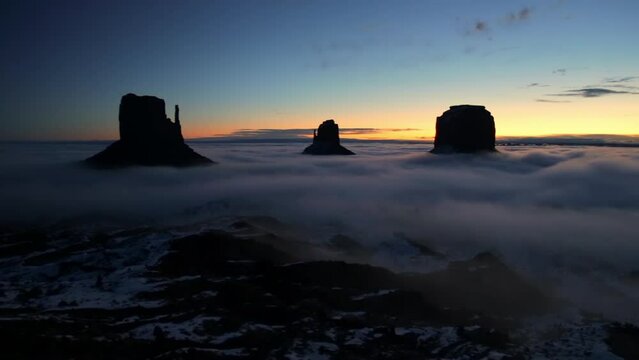 Monument Valley at sunrise in winter with white snow and clouds, USA