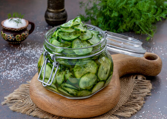 Pickled cucumbers. Slices of marinated cucumber salad in glass jar with bunch of dill. Homemade fermented cucumbers. Selective focus, horizontal.