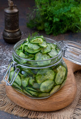 Pickled cucumbers. Slices of Marinated cucumber salad in glass jar with bunch of dill. Homemade fermented cucumbers. Selective focus, vertical.