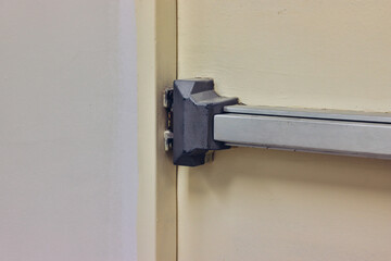 Emergency fire exit door. Closed up latch and rusty door handle of emergency exit. Push bar and...