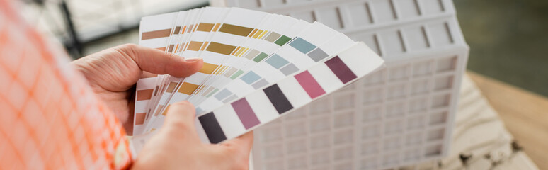 cropped view of designer holding color palette near residential house model in office, banner.