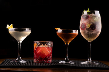 cocktail collection with vesper negroni weesky and lillet with berries and mint in bar rubber holder on black background