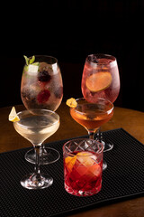 cocktail collection with vesper negroni whiskey and lillet with berries and mint and lime in rubber bar holder