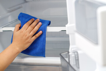 Employees use a cloth to clean the refrigerator.