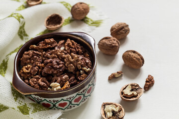 Bowl with fresh peeled walnuts and whole walnuts on a white background. Copy space.