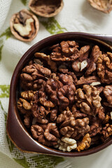Fresh organic walnut kernels close up in a brown ceramic bowl. Top view.