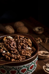 Organic dried walnut kernels close up in a ceramic bowl on a wooden background. Healthy eating concept.