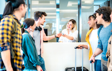 Young millenial friends having fun time at hotel reception desk on check in time - Travel life style concept with happy people waiting at guesthouse desk on fancy vacation - Bright vivid filter - 589916983