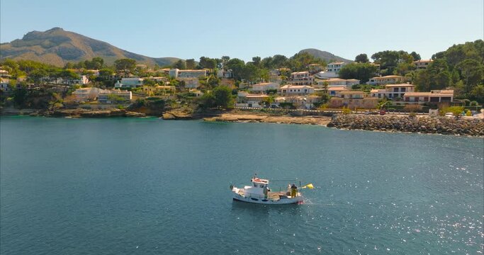 Barco con pescador pescando con casas de fondo, mediterr&aacute;neo (DJI Inspire 3)	