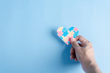 Hand holding Awareness heart jigsaw puzzle, Color puzzle symbol of awareness for autism spectrum disorder family support. Autism World Awareness Day.