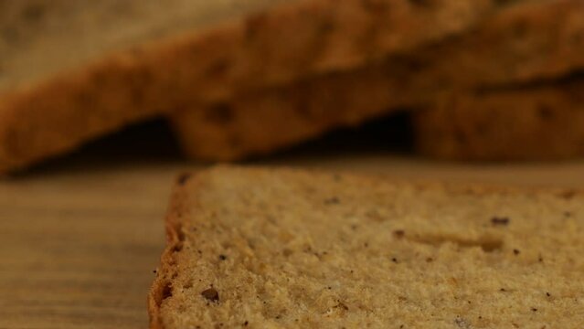 Cream cheese spread with a knife on a piece of multigrain bread on a wooden cutting board.