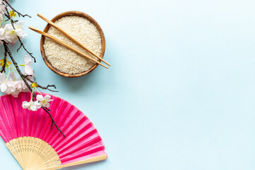 Asian table setting - rice bowl with cherry branch and fan. Top view