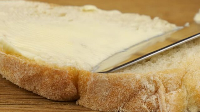 Cooking a sandwich from white bread and butter with red caviar on a wooden cutting board.