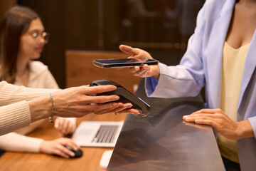 Stylish visitor making contactless transaction at lobby desk