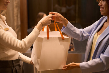 Female worker giving to customer package in lobby