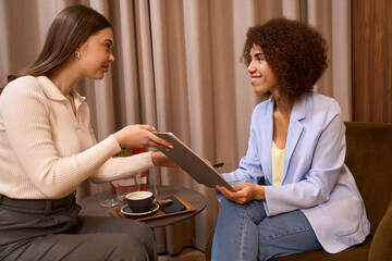 Fototapeta premium Elegant worker showing clipboard to pretty client at cafe
