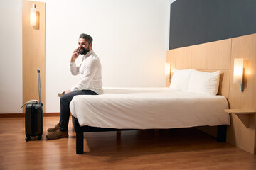 Joyous businessman talking on smartphone in his luxury suite