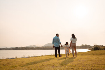 Happy Family enjoying a peaceful walk and running in a scenic field with a serene lake in the background.