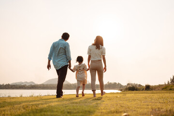 Happy Family enjoying a peaceful walk and running in a scenic field with a serene lake in the background.