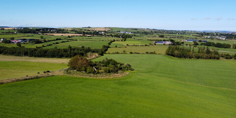 Vast green pastures for cattle in the south of Ireland. Picturesque farmland, top view. Agricultural landscape on a sunny summer day. Nature. Green grass field under blue sky
