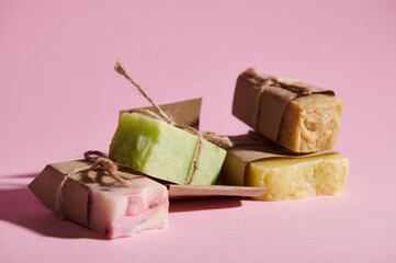 Assortment of multi-colored cold-pressed organic soaps with natural herbal and floral ingredients on isolated pink background. Still life. Hair, skin and body care concept. Home sp. Hygiene. Purity