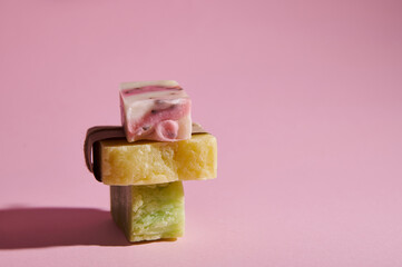 Stack of homemade natural eco soap bars with organic herbal and floral ingredients for health and spa, isolated on pink background. Purity. Hygiene. Skin and body care concept