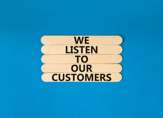 We listen to our customers symbol. Concept words We listen to our customers on wooden stick. Beautiful blue table blue background. Business we listen to our customers concept. Copy space.