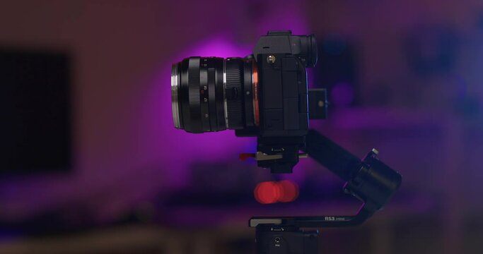 Close-up cropped shot of unrecognizable male videographer testing professional modern electronic stabilization system of steadicam with camera installed, on dark background. Shooting in slow motion.