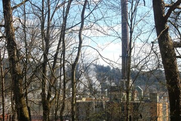 Blick auf eine Papierfabrik durch Bäume. Qualmende Kamine. Schongau, Bayern.