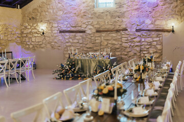 Long festive wooden table, which is decorated with lemons, flowers and greenery, on the table are plates, glasses and candles. Wedding in Italy. Tuscany