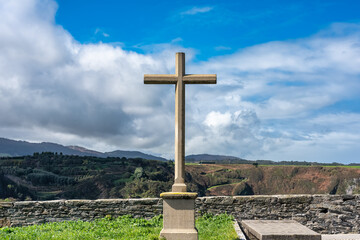 Fototapeta na wymiar Stone cross in front of the cliffs of the Cantabrian Sea in the tourist town of Luarca, Asturias.