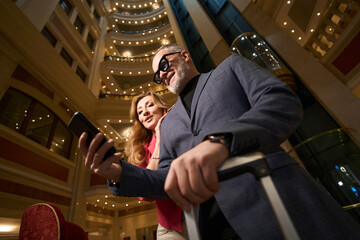 Man with phone and beautiful woman in lobby of hotel