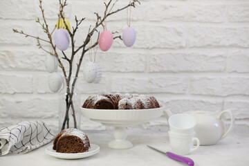 Easter background with eggs and spring branches. Happy Easter. Table setting with easter pie and a piece of pie on white bricks background. Holidays background.