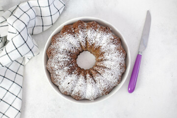 Chockolate cake with purple knife and napkin on gray background.