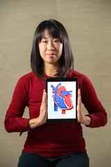 Woman holding a screen with a heart cutout design.