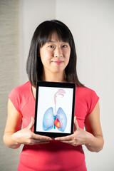 Fototapeta premium Woman holding screen with drawing of heart and lungs.