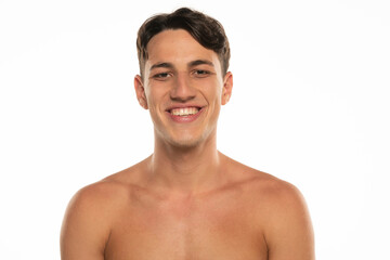 Fototapeta premium Closeup portrait of smiling shirtless man 20s looking at camera isolated over white background