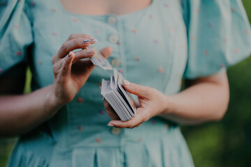 Woman shuffles playing cards or tarot deck. Fortune teller, medium, divination