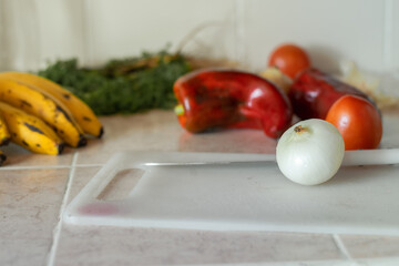 close-up of an onion on the chopping board with other red vegetables in the background