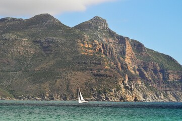 sailing boat in the distance with mountain formation 