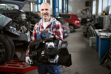 Man in plaid shirt with car spare part in his hands