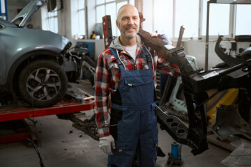 Strong master holds part of car body on his shoulder