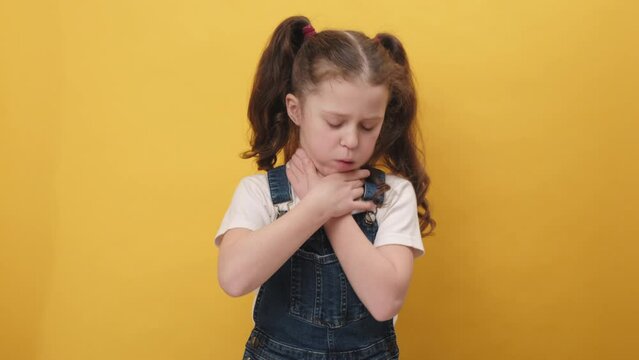 Portrait of unhealthy preteen girl kid coughing covering mouth with hand, feeling sick, allergy or viral infection symptoms, posing isolated on yellow background wall. Disease, flu, infection concept