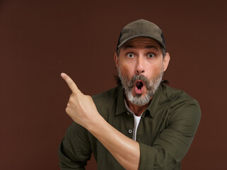 Middle-aged Caucasian country man expresses extreme surprise, pointing his finger to the side. Copy...