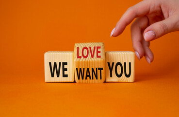 We love and want You symbol. Businessman Hand points at turned wooden cubes with words We want you and We love you. Beautiful orange background. Business and We love and want You concept. Copy space