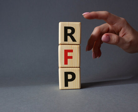 RFP - Request for Proposal. Wooden cubes with word RFP. Businessman hand. Beautiful grey background. Business and Request for Proposal concept. Copy space.