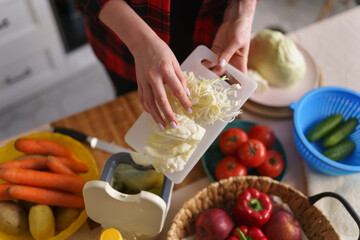 Cook throwing food leftovers in a bokashi bin for compost. Female person recycling compostable organic waste at home