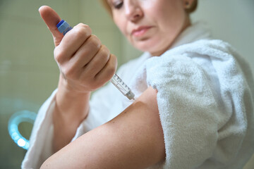 Female gives herself an injection in the arm