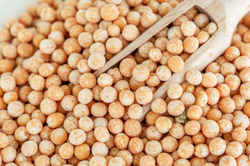 Dry golden peas with a wooden scoop. Health and natural products. Close-up.